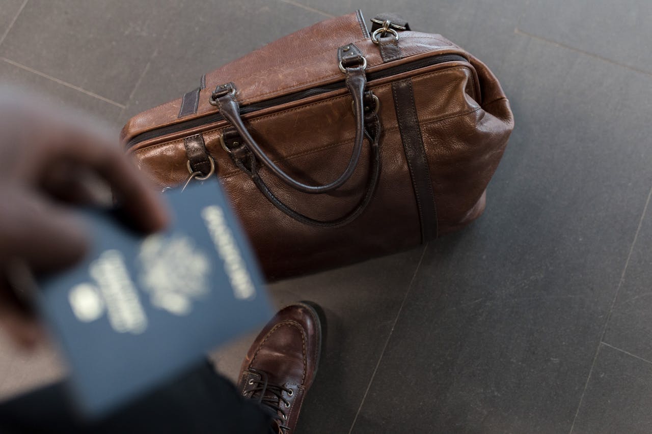 The Art of Drawing Readers In: Your attractive post title goes here Brown leather bag with passport in an airport setting, ideal for travel and fashion themes.