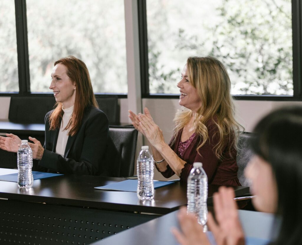 Focused business professionals clap during a conference meeting, capturing positive engagement.